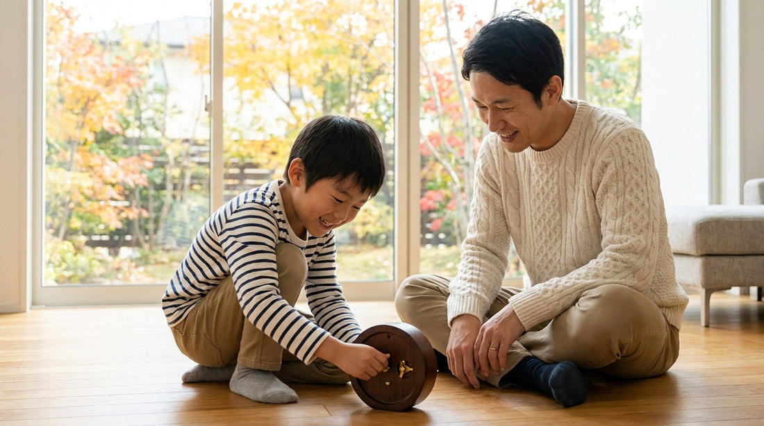 リビングの床で、男の子が置き時計の裏のつまみを回して遊び、となりで大人の男性がほほえんで見ている様子
