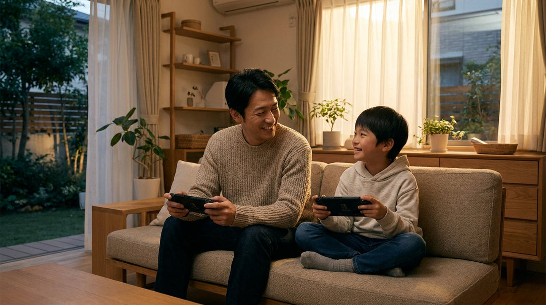 ソファに並んで座り、携帯ゲーム機を持って笑い合う大人の男性と男の子